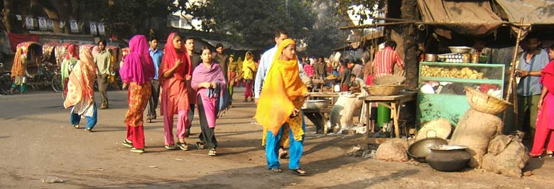 In den Straßen von Dhaka sieht man nur selten eine Frau. Morgens und abends zwischen sieben und halb acht jedoch ziehen farbenfrohe Schwärme von Frauen durch die Straßen. Schichtwechsel in den Textilfabriken. Sie laufen oft weite Wege bis zur Arbeit, weil sie sich Busse oder Rikschas nicht leisten können.